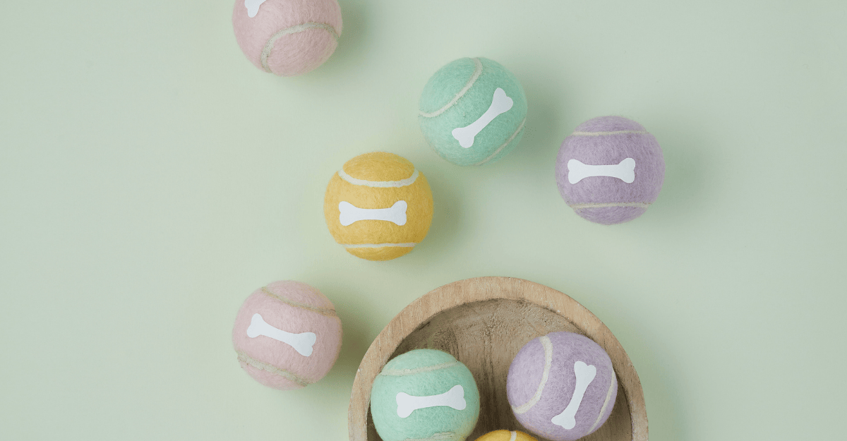 Pastel colour tennis balls with bone design scattered on green background and in wooden bowl
