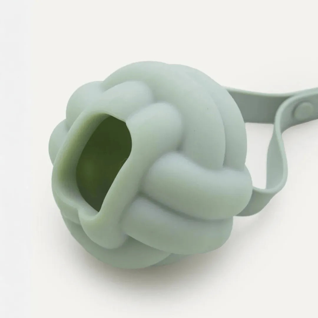 Close-up of sage green silicone knot ball dog toy showing hollow treat-filling opening, maxbone Enrichment