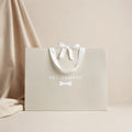 Beige Pet Hamper branded gift bag with white ribbon bow and bone logo