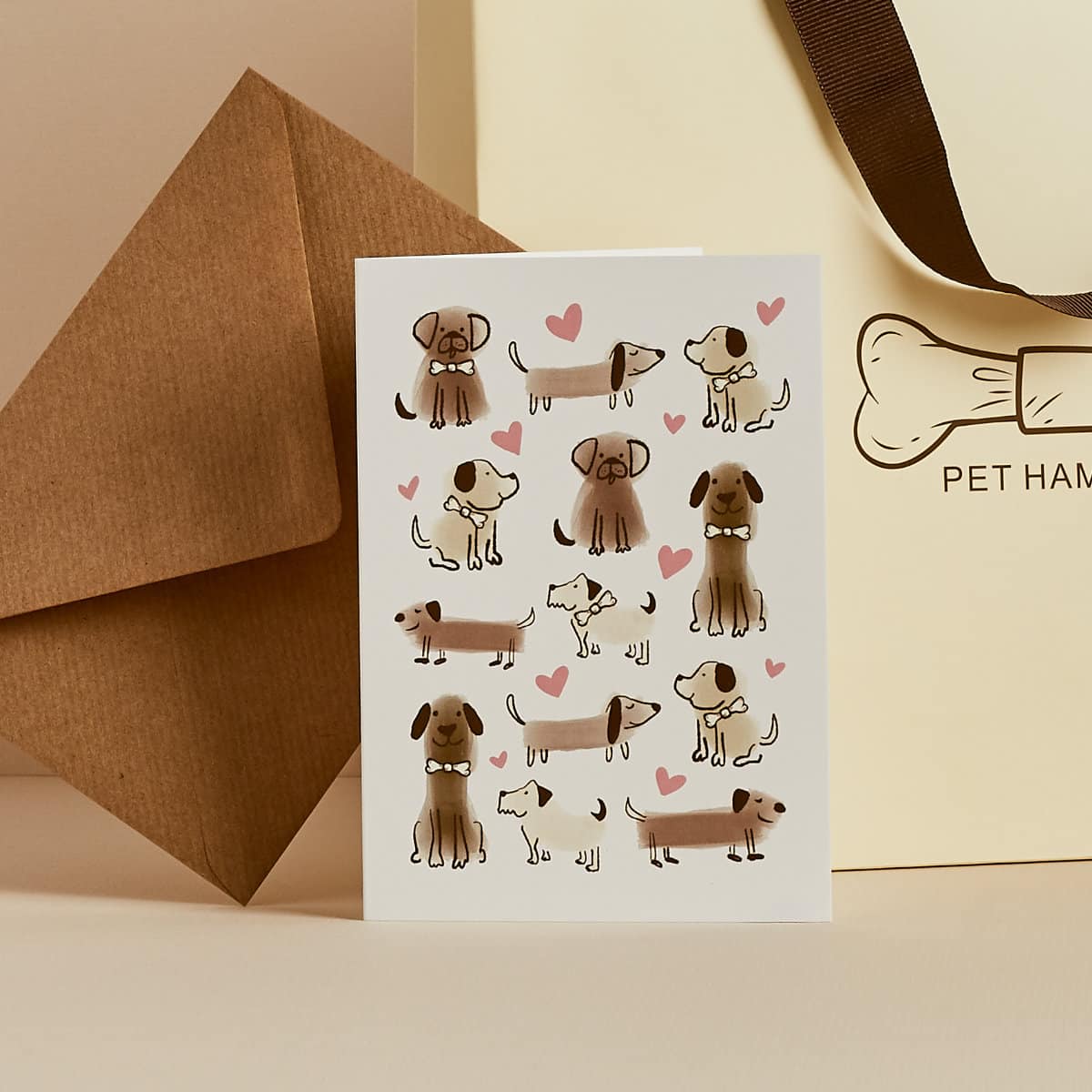 White greeting card with illustrated dogs and hearts, kraft envelope and Pet Hamper gift bag