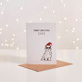 White Christmas card with illustrated dog in Santa hat and sunglasses, 'Merry Christmas' text, kraft envelope