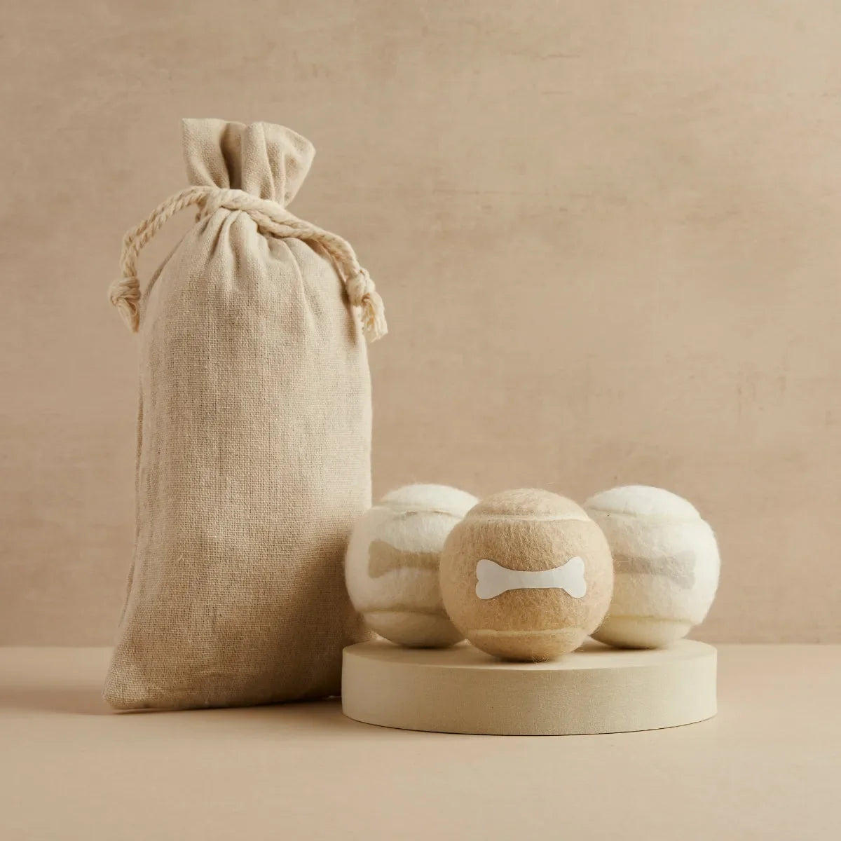 Three neutral tone tennis balls with bone design and linen bag, Pet Hamper