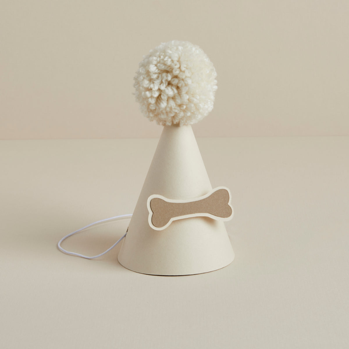 Cream dog party hat with wool pom-pom and bone decoration