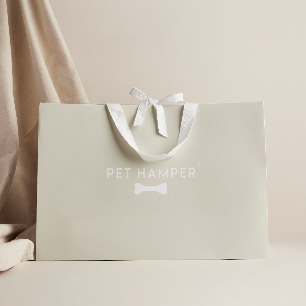 Beige Pet Hamper branded gift bag with white ribbon bow, Small Animal Hamper banner