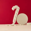 Beige braided rope candy cane dog toy with vanilla scent, red backdrop