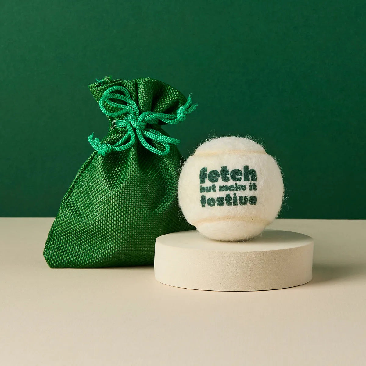 White tennis ball printed with 'Fetch But Make It Festive' text and green gift bag, Pet Hamper